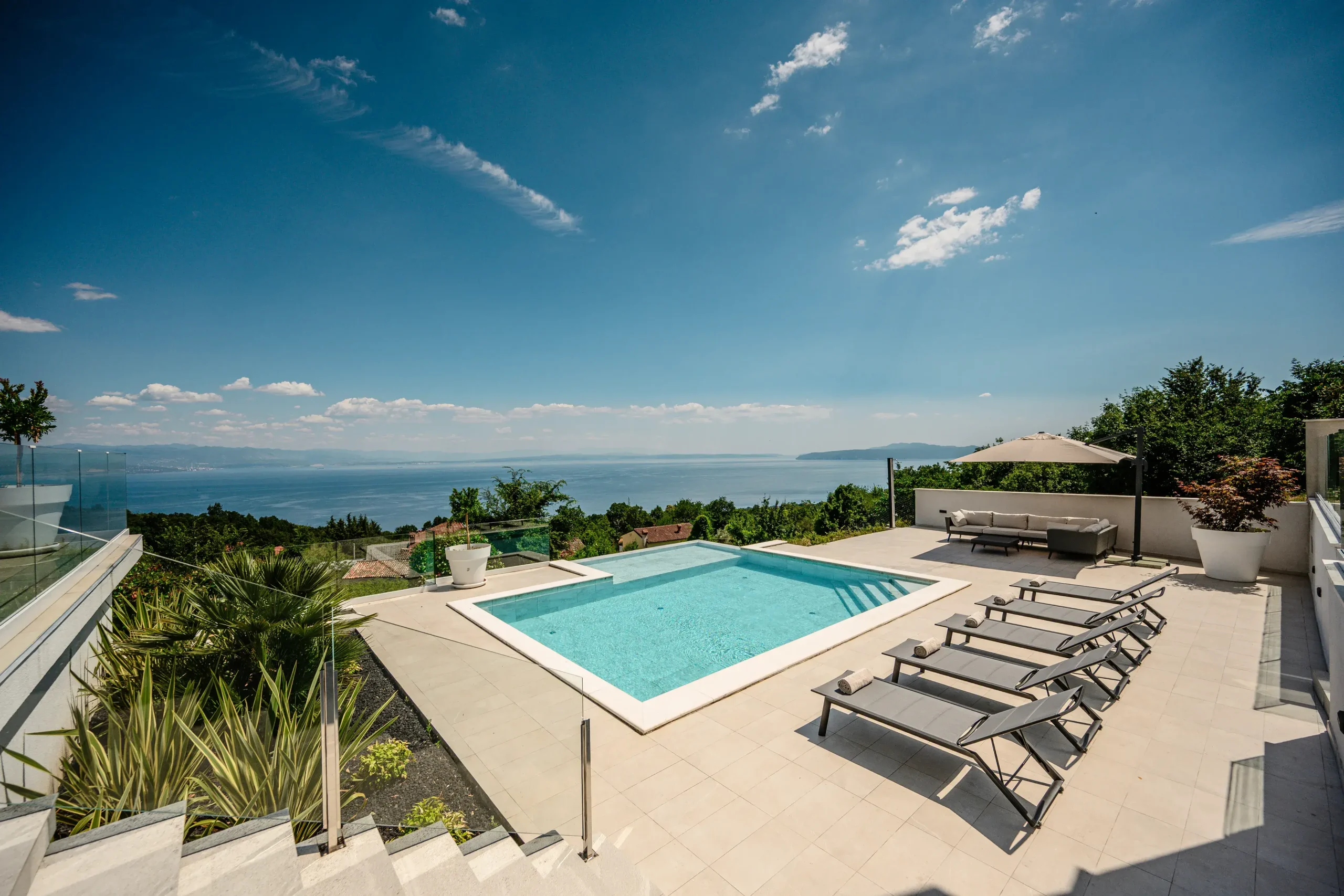 Infinity pool and sun loungers with panoramic daytime view of the Kvarner Bay near Opatija