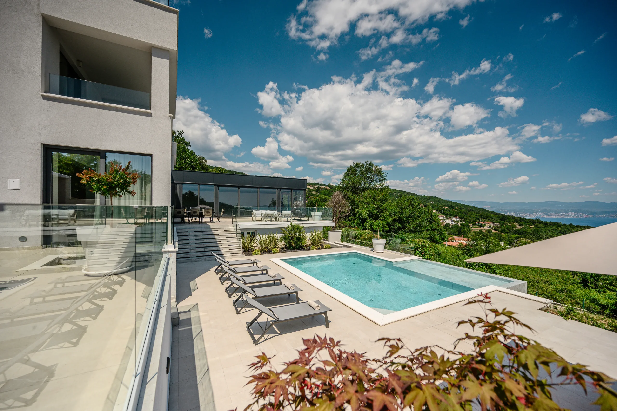 Outdoor dining and egg chair lounge on Villa Theodor's terrace surrounded by forested hills