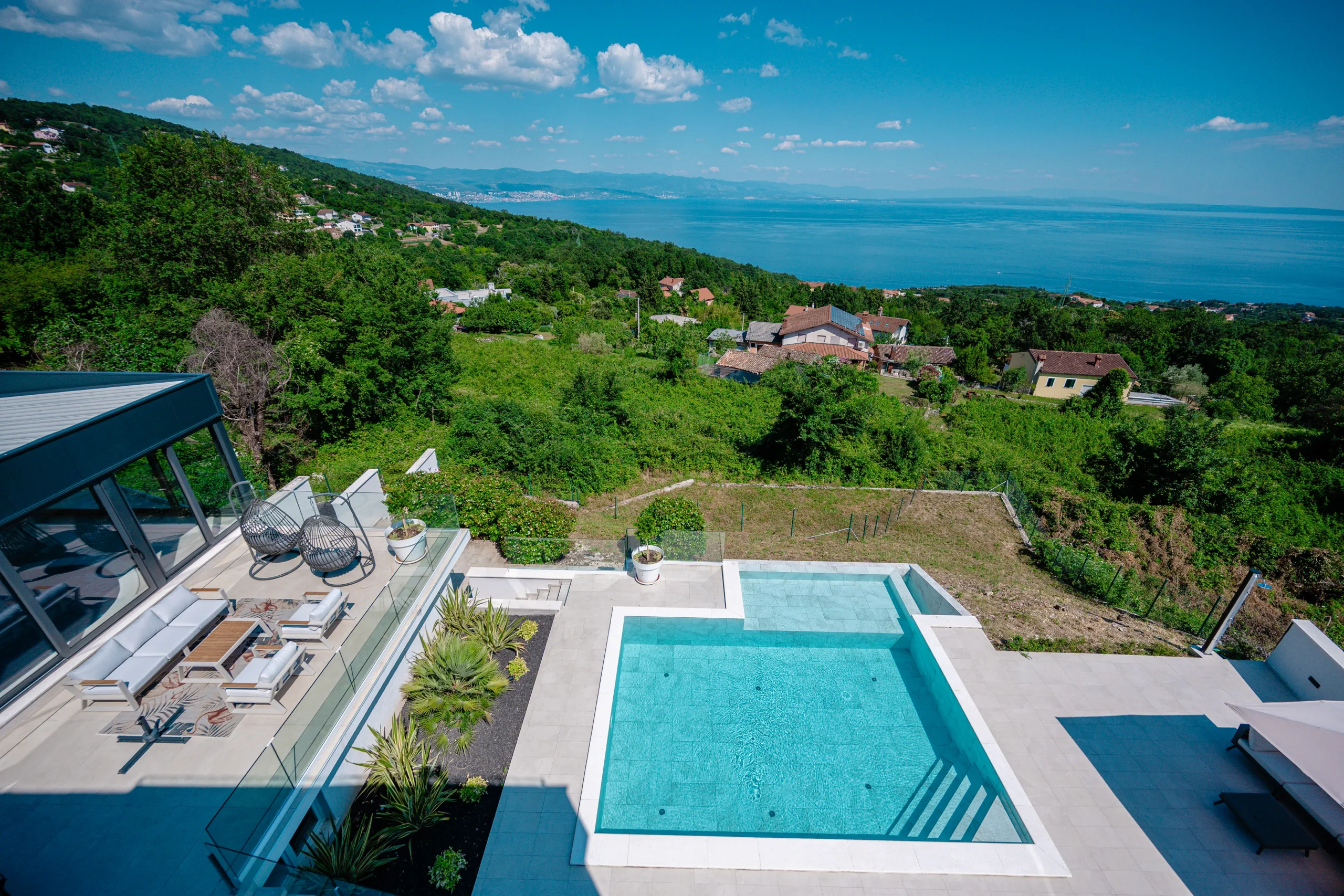 Wide view of Villa Theodor's pools and terraces set within the green hillside landscape above Opatija