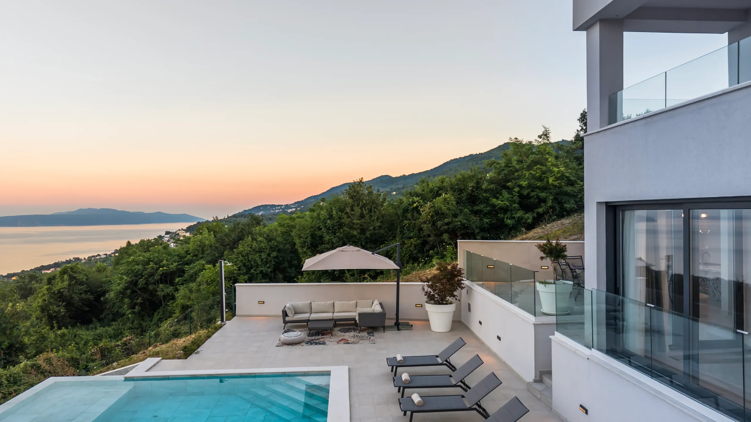 Villa Theodor's terrace lounge at sunset with panoramic views over the forested hillside and sea