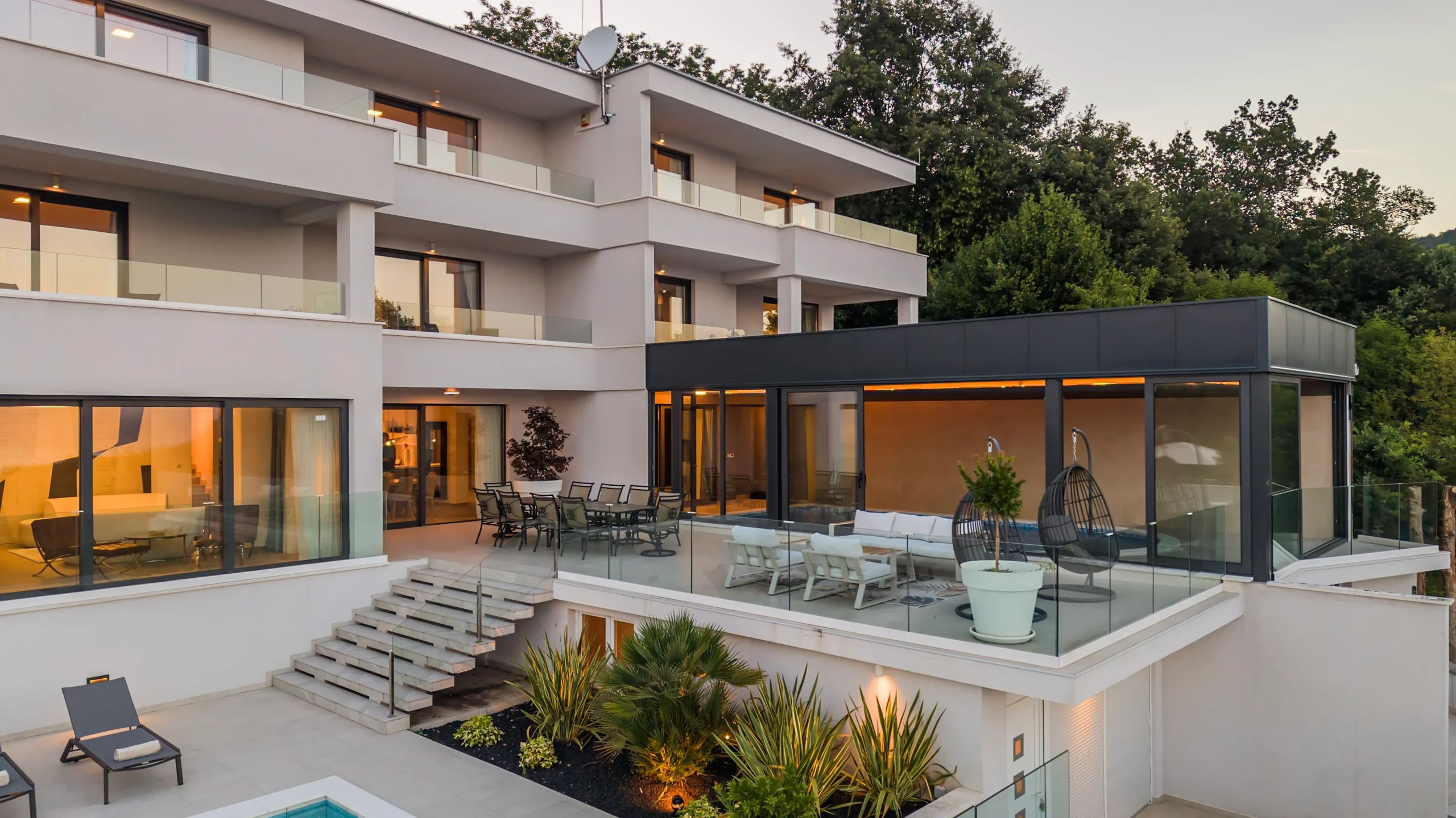 Villa Theodor's dining and lounge terraces at dusk with sea and hillside views