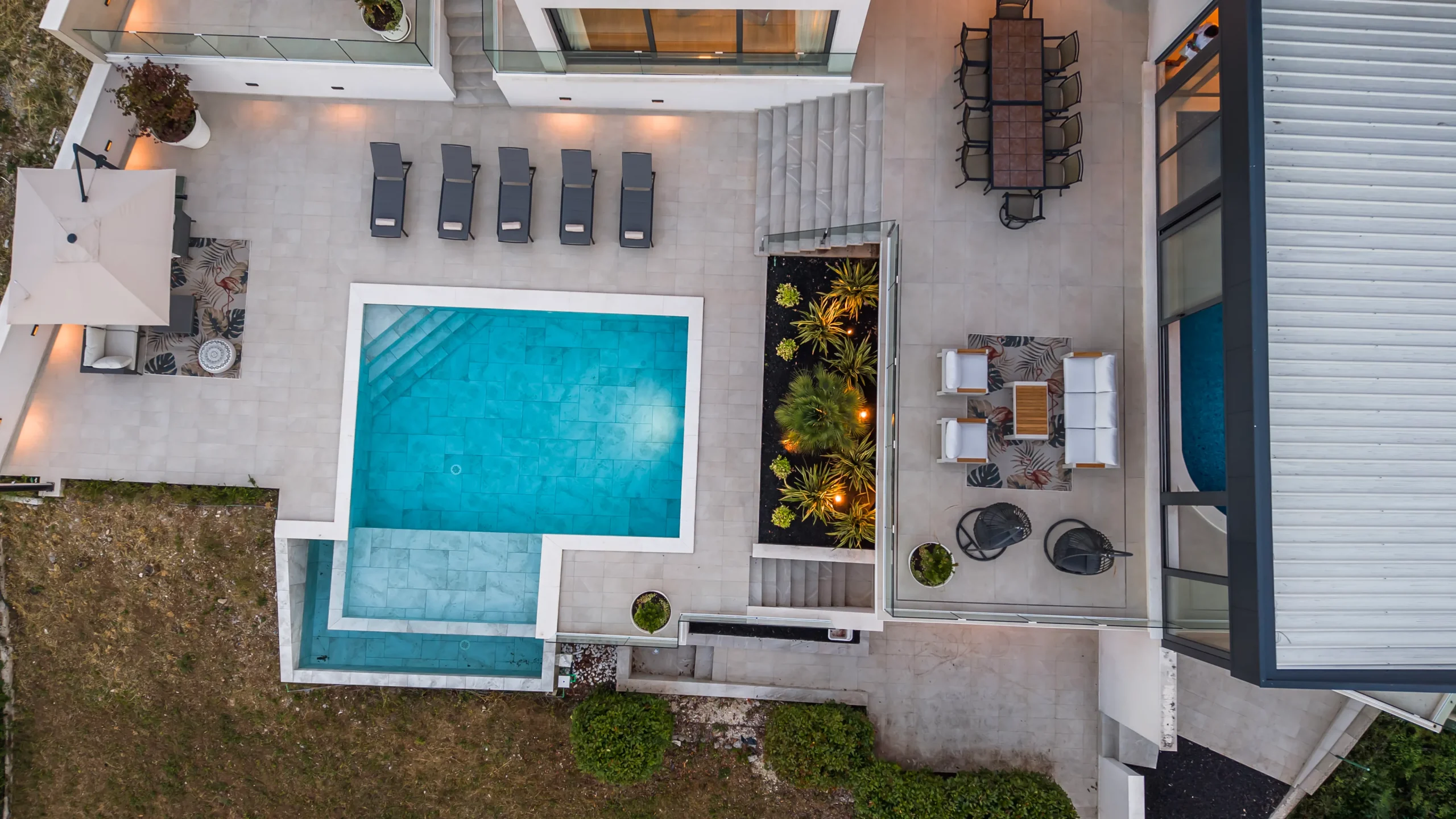 Aerial view of Villa Theodor's pool terrace with dining area and illuminated garden bed