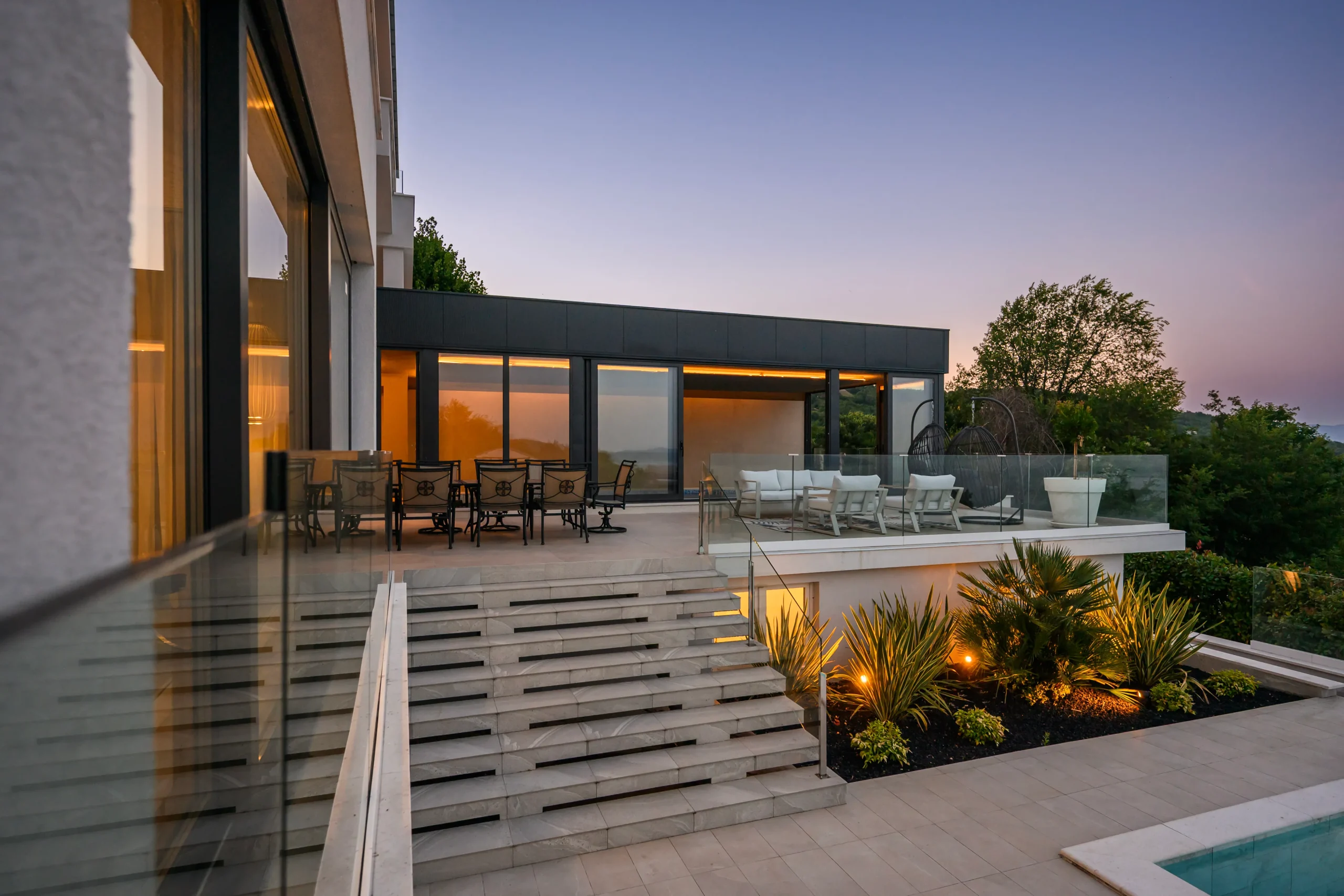 Villa Theodor's dining and lounge terrace under a twilight sunset sky over the hills